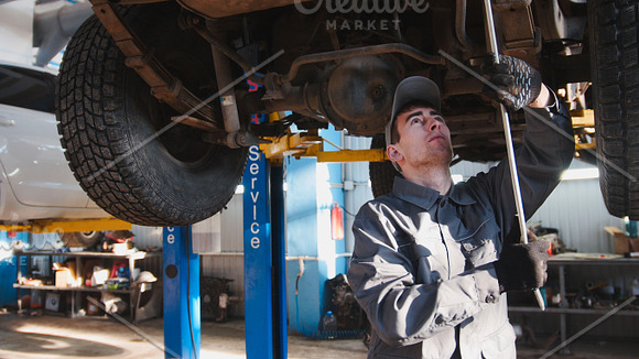 Garage automobile service - a mechanic checks the suspension in Graphics