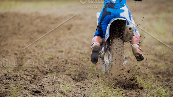 Motocross racer start riding his dirt Cross MX bike kicking up dust rear view, close up in Graphics