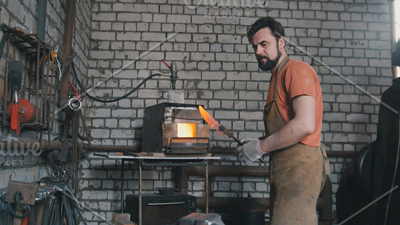 Young muscular man working on a blacksmith with metal in Graphics