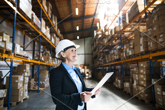 Senior Woman Warehouse Manager Or Supervisor With Tablet Working